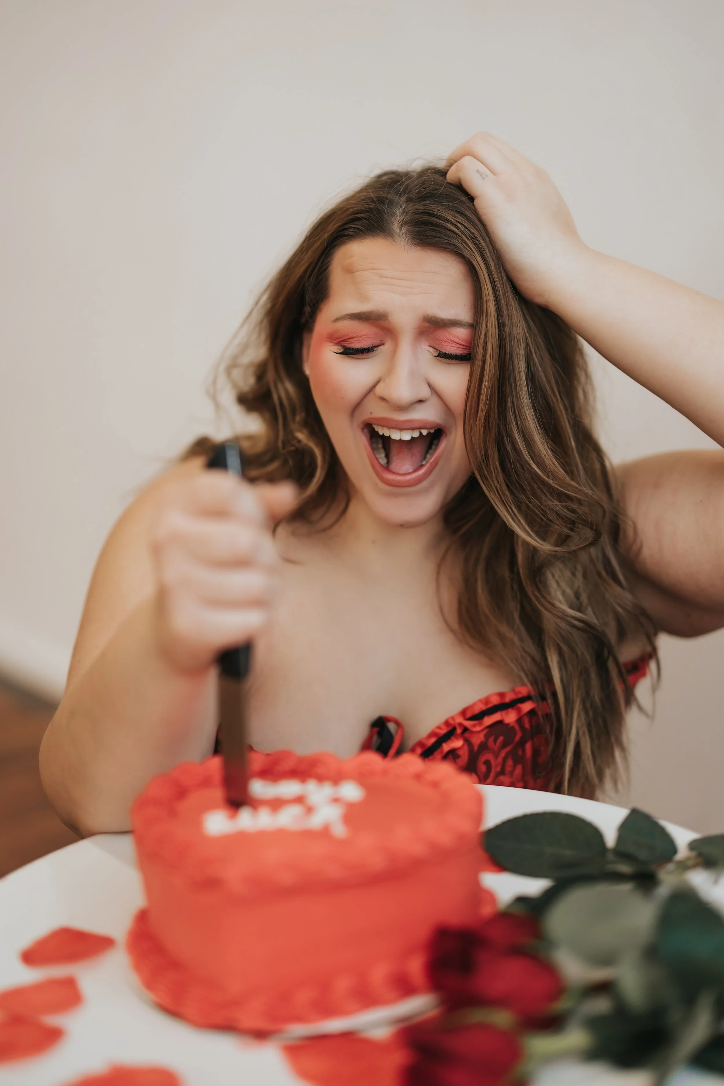  Fashion model poses with an anguished expression while stabbing a knife in a heart-shaped cake for a creative Valentine’s Day photoshoot. 