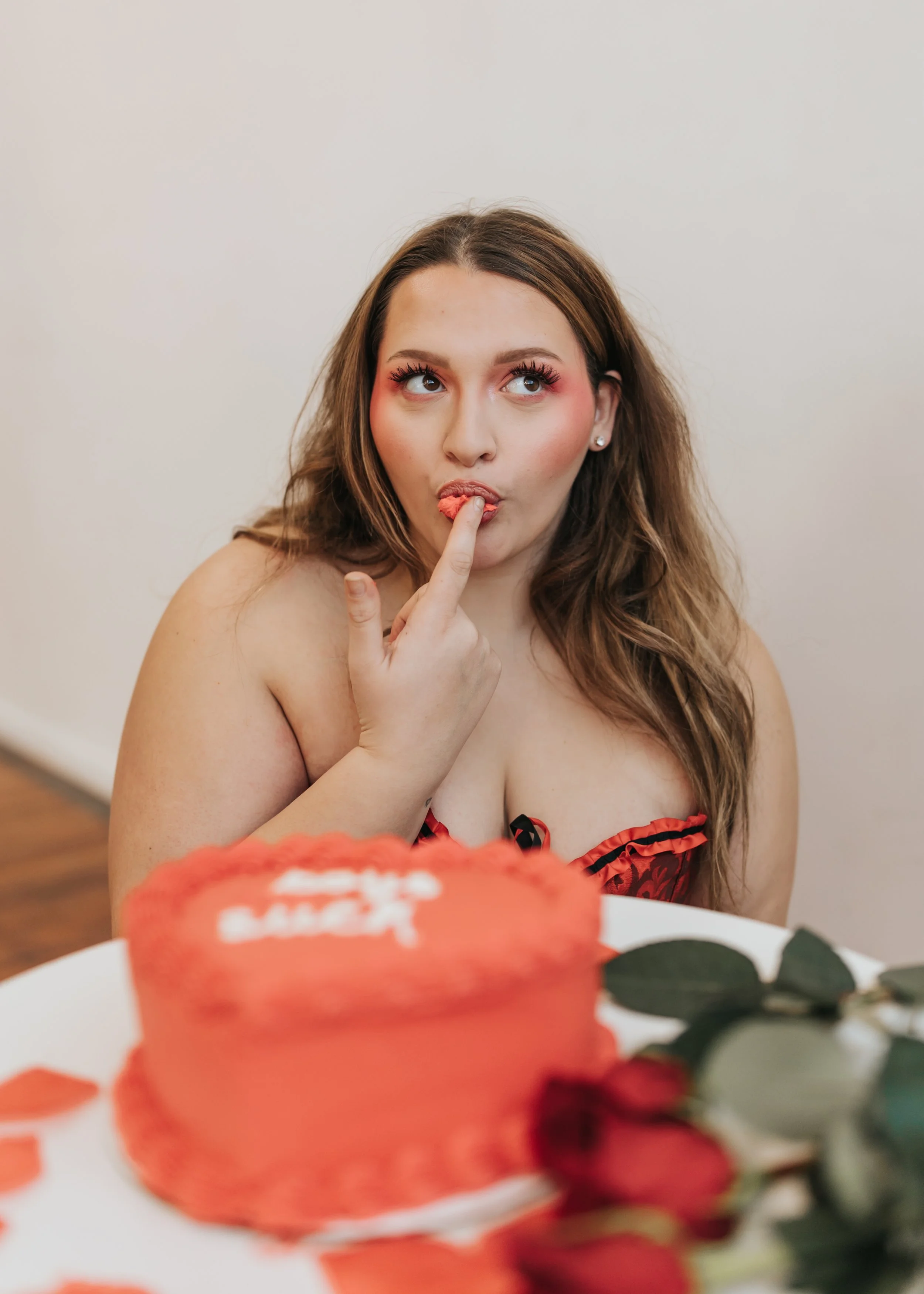  Fashion model poses with a heart-shaped cake while licking frosting from her hands for a creative Valentine’s Day photoshoot. 