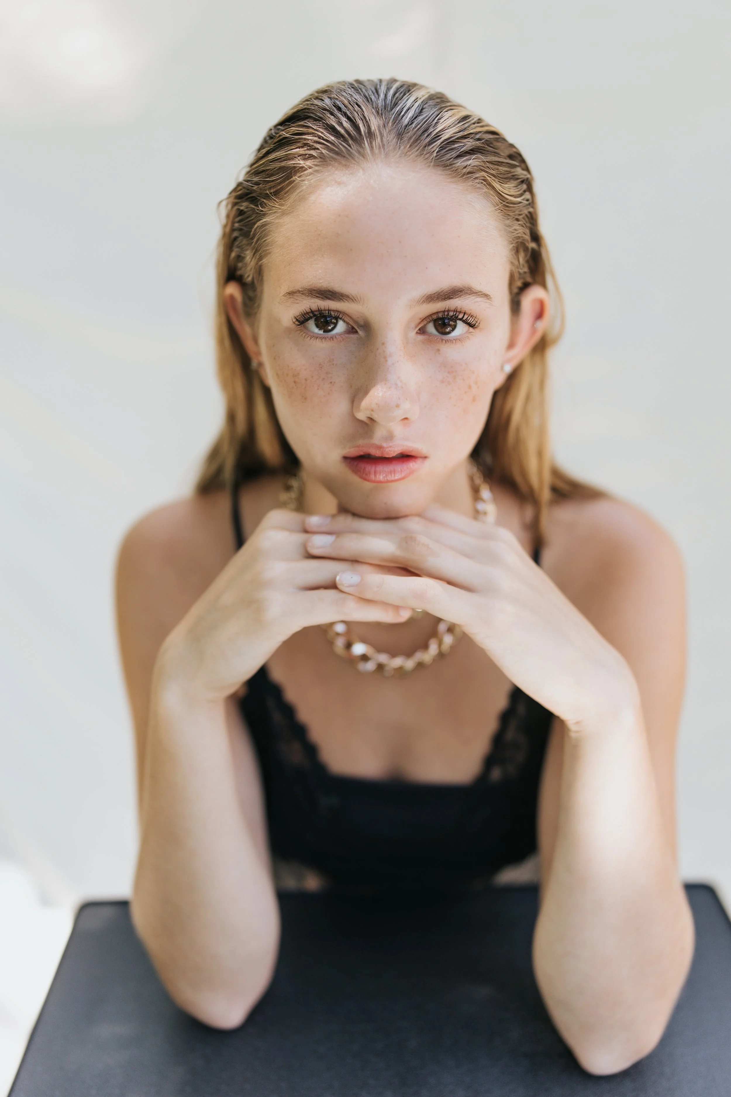  Close up fashion photo of a blonde model leaning into her hands. 