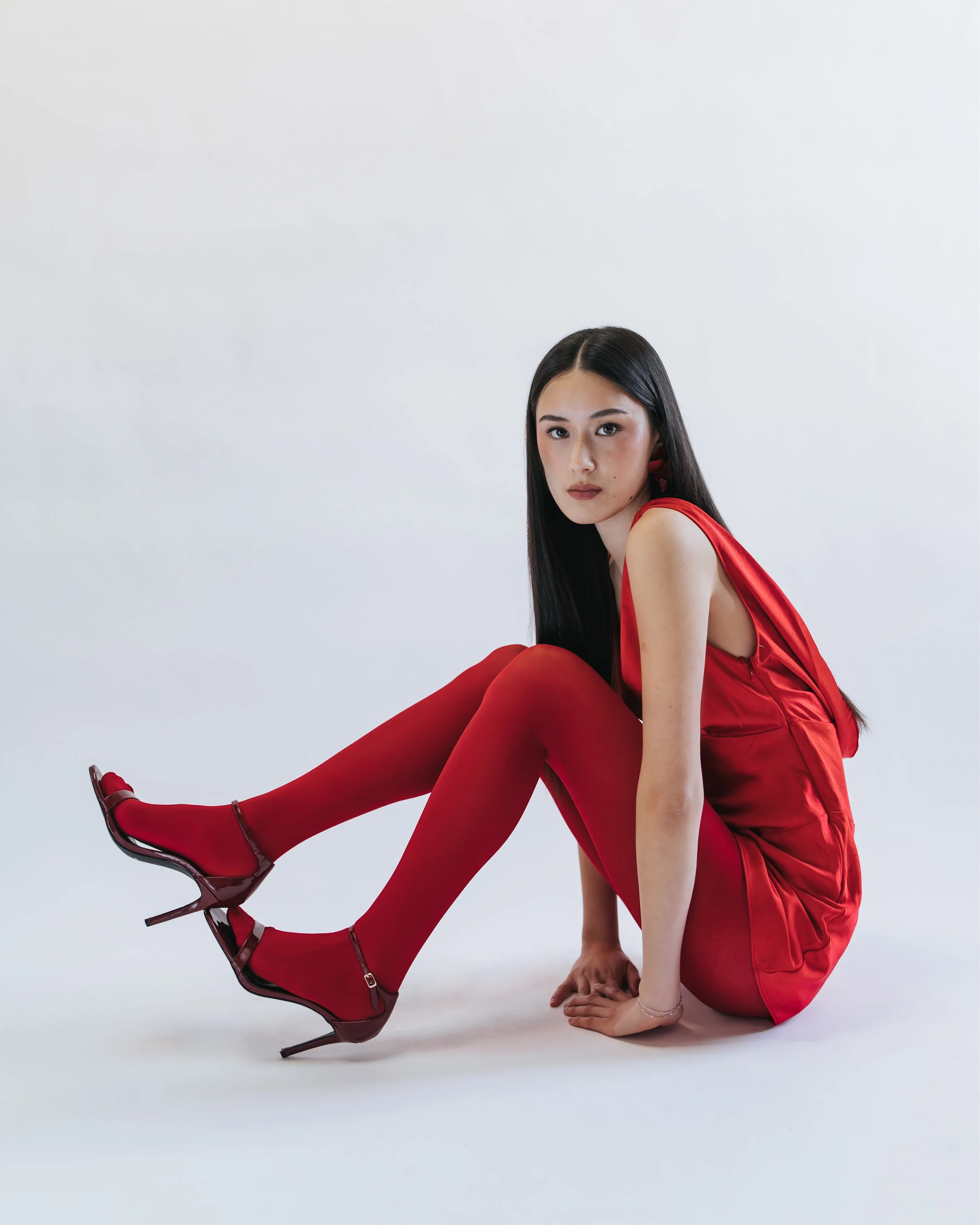  Dark haired model poses for a Valentine’s themed test shoot wearing an all-red outfit. 