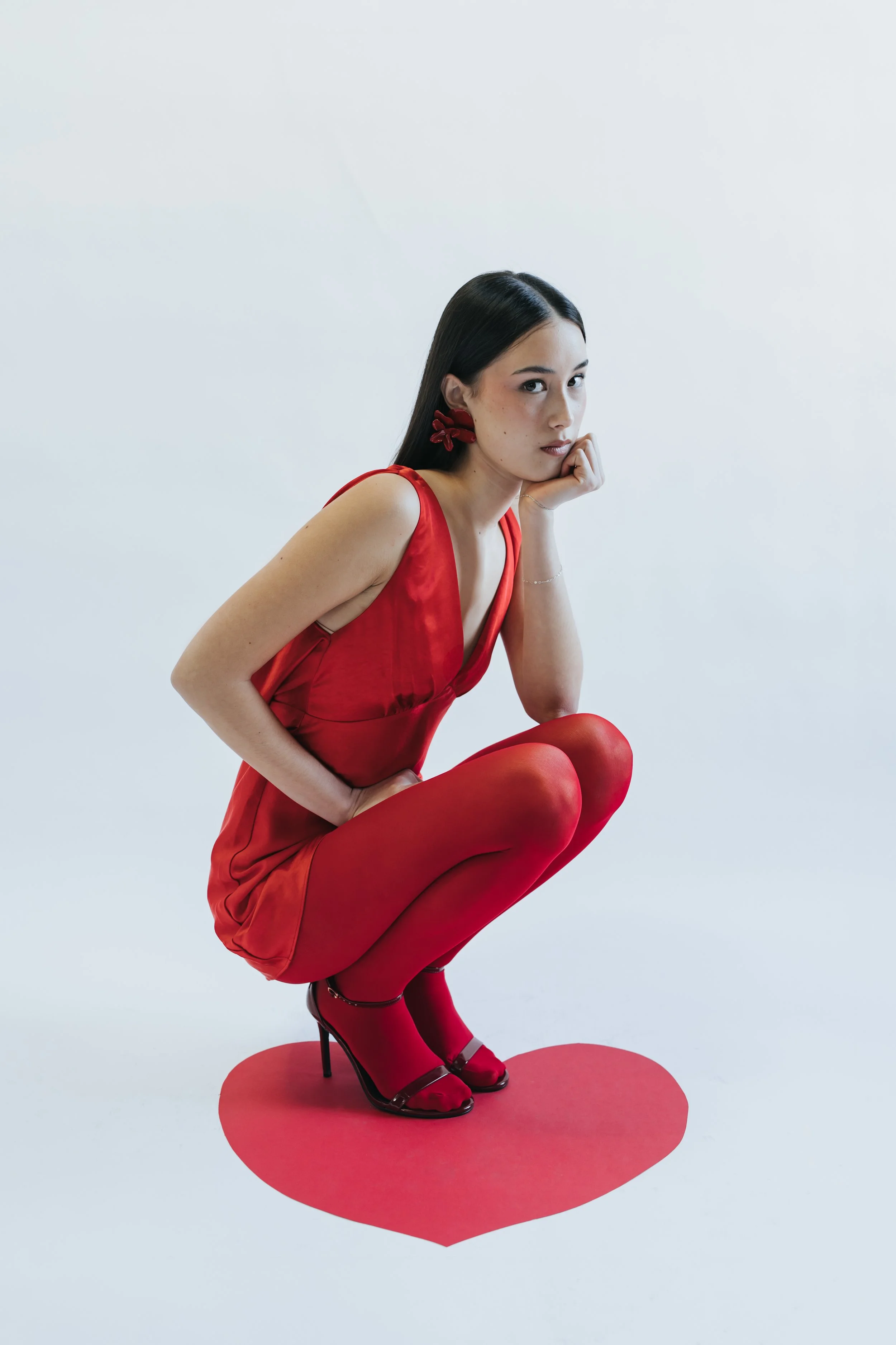  Dark haired model poses for a Valentine’s themed test shoot wearing an all-red outfit. 