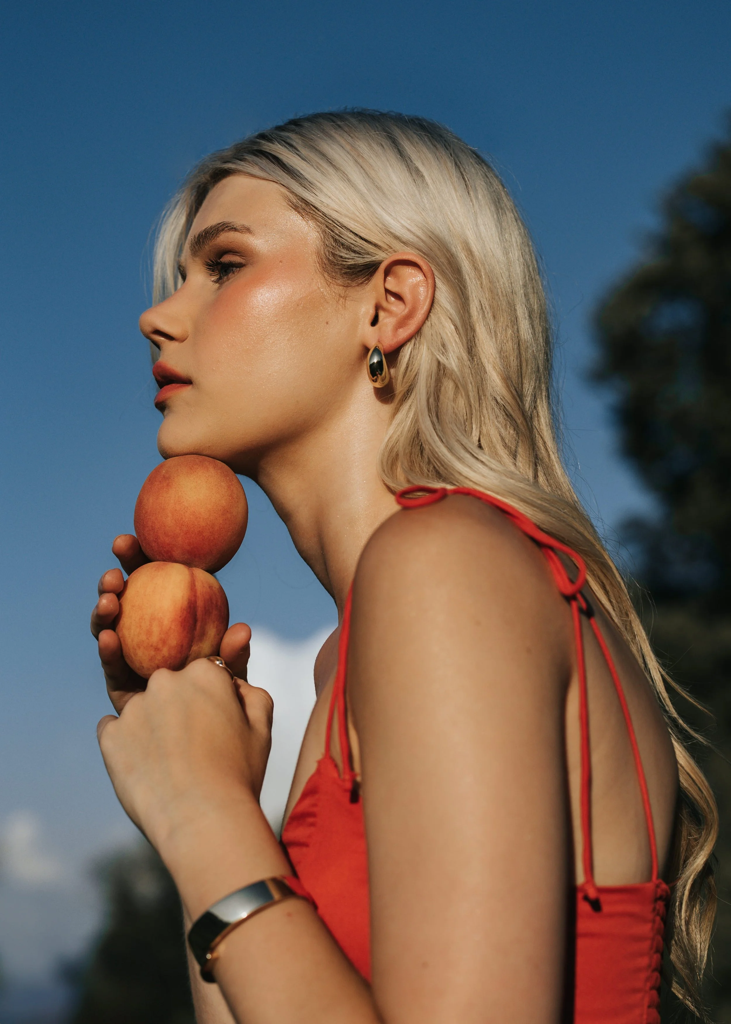  Blonde model poses holding a stack of peaches during her fashion photoshoot. 