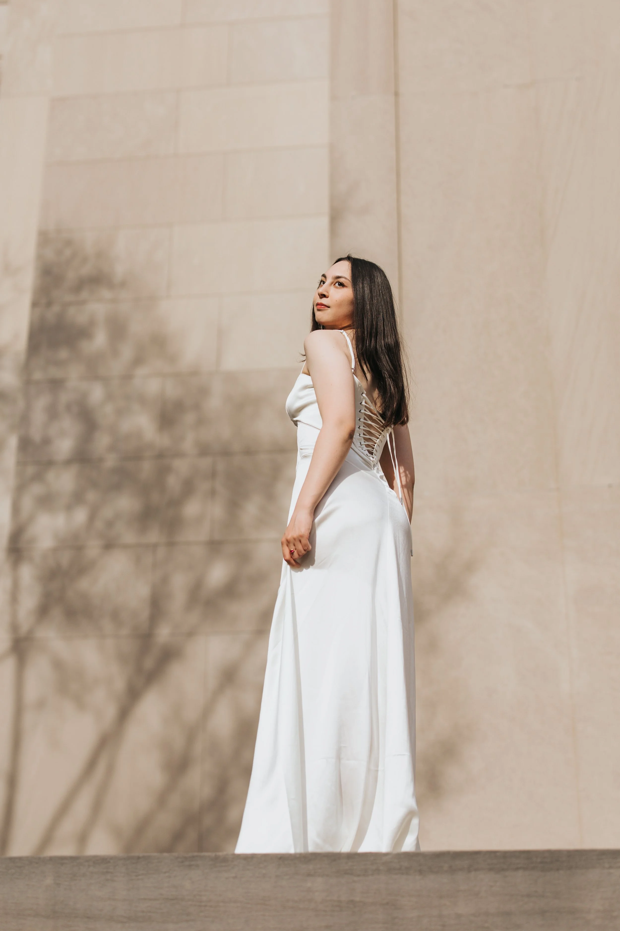  Claire, an MIT graduate, poses for her Boston graduation photos in a long white dress at the Main Entrance of the MIT campus 