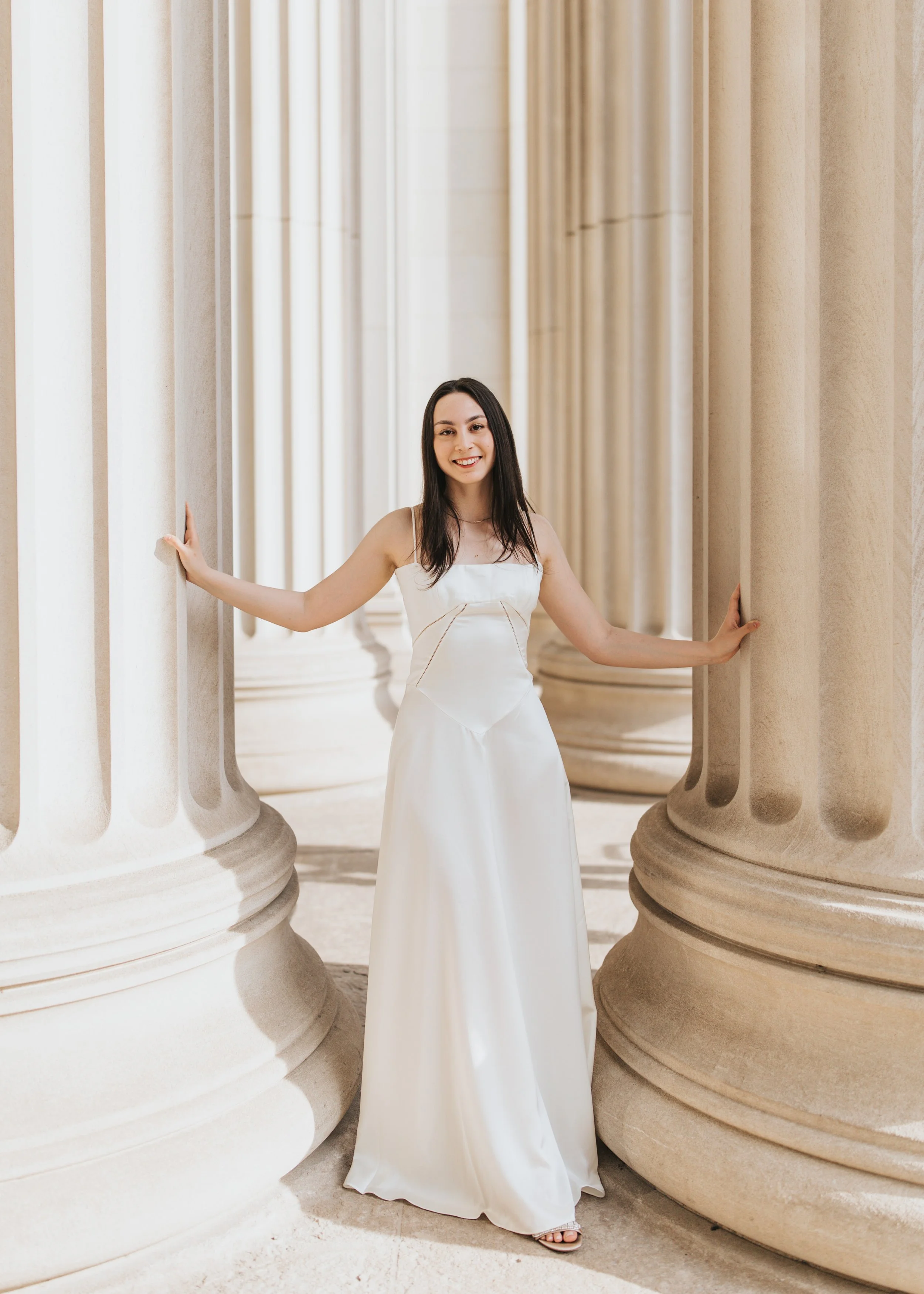  Claire, an MIT graduate, poses for her Boston graduation photos in a long white dress at the Main Entrance of the MIT campus 