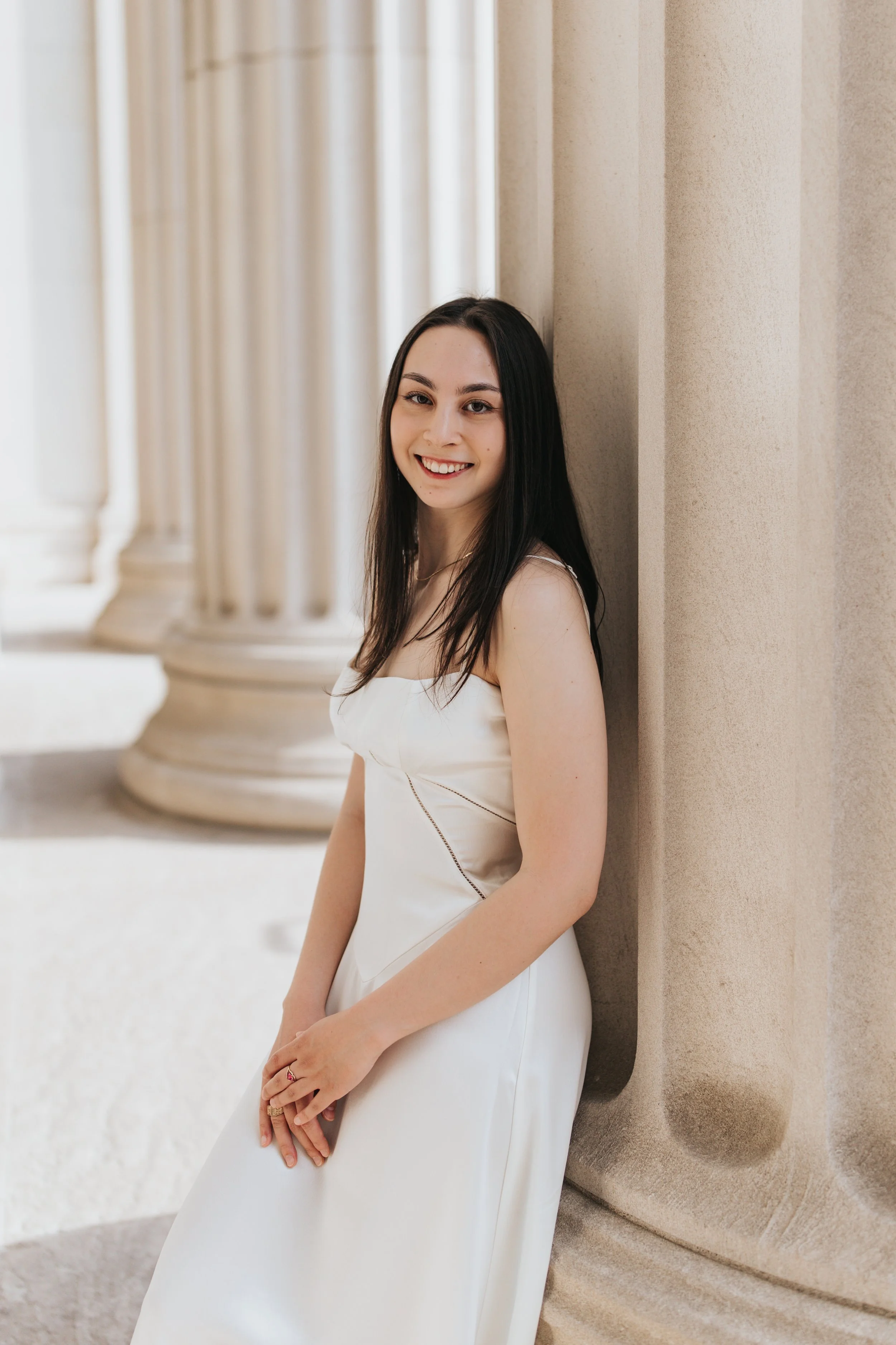  Claire, an MIT graduate, poses for her Boston graduation photos in a long white dress at the Main Entrance of the MIT campus 