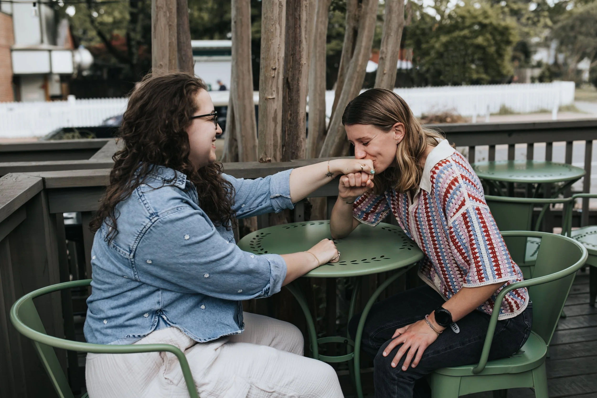  Maddie and Sarah sitting at a coffee shop during their LGBTQ+ engagement photoshoot in Nashville. 