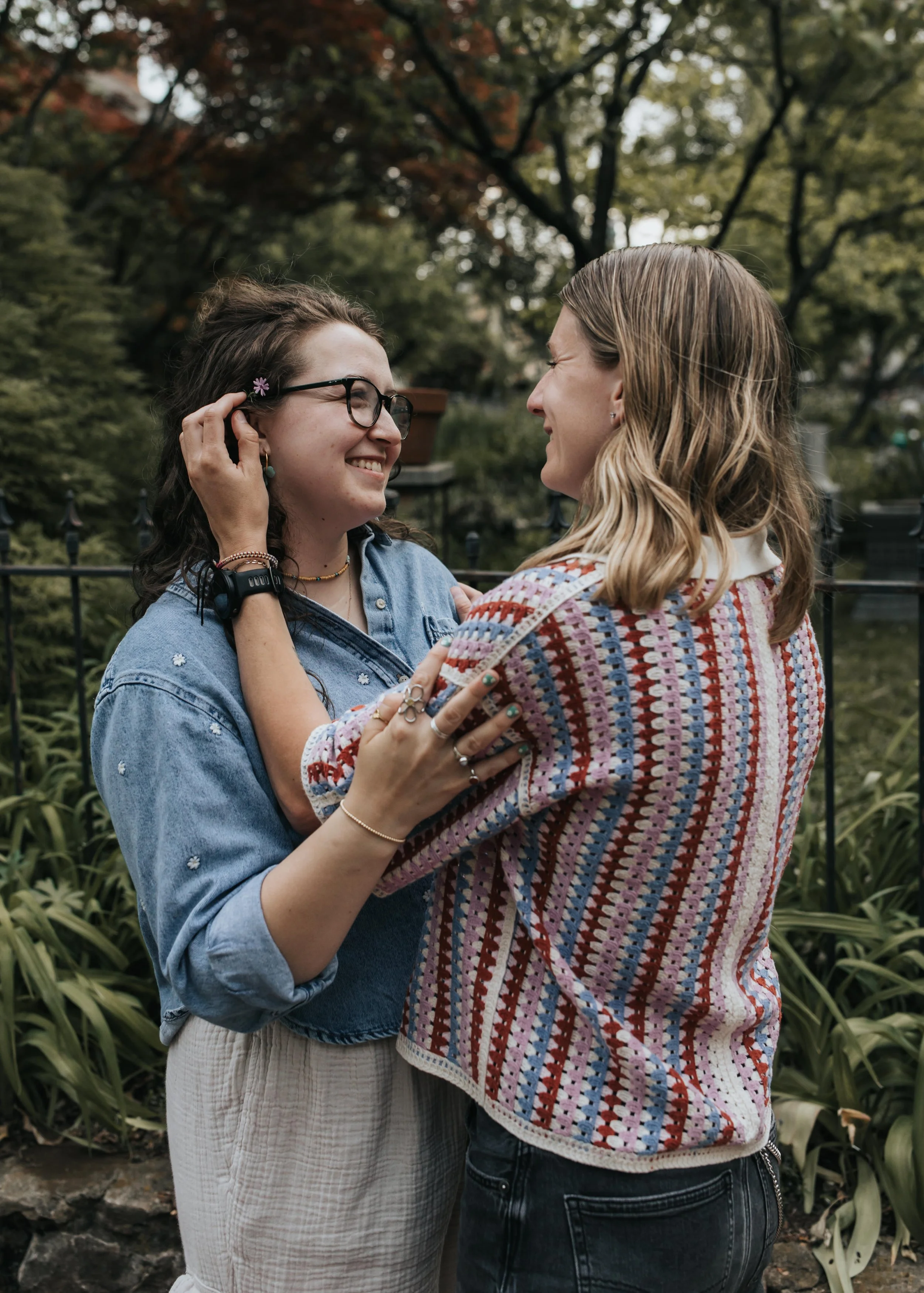  Maddie puts a flower in Sarah’s hair during their engagement photoshoot. 