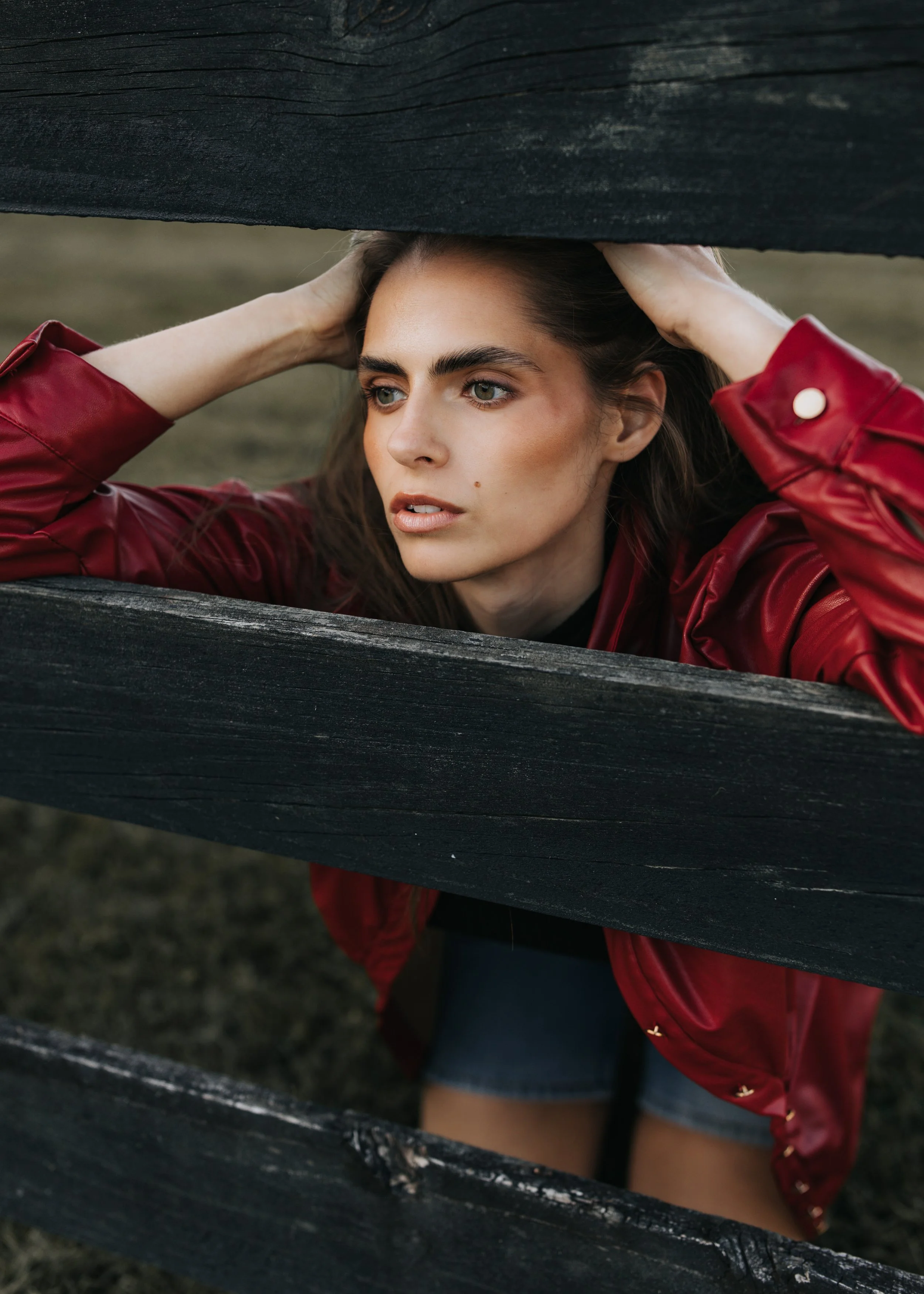  Model Skylar poses between a fence while wearing a red jacket during her Nashville fashion photoshoot. 