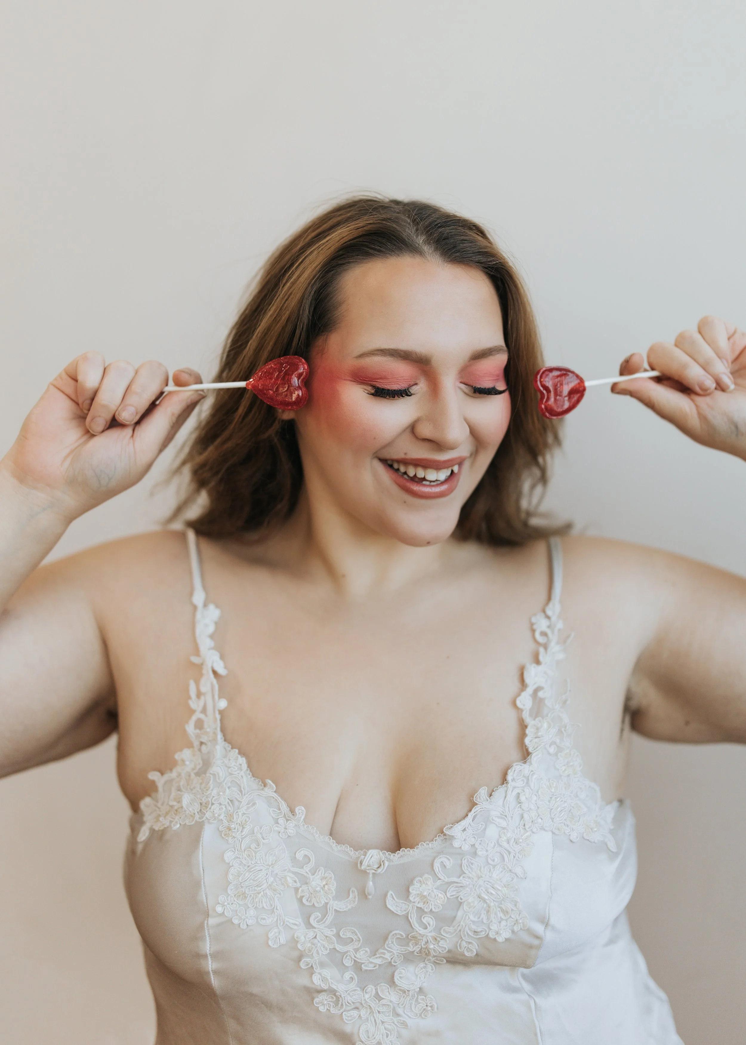 Model poses with heart-shaped lollipops for a creative Valentine’s Day fashion photoshoot.