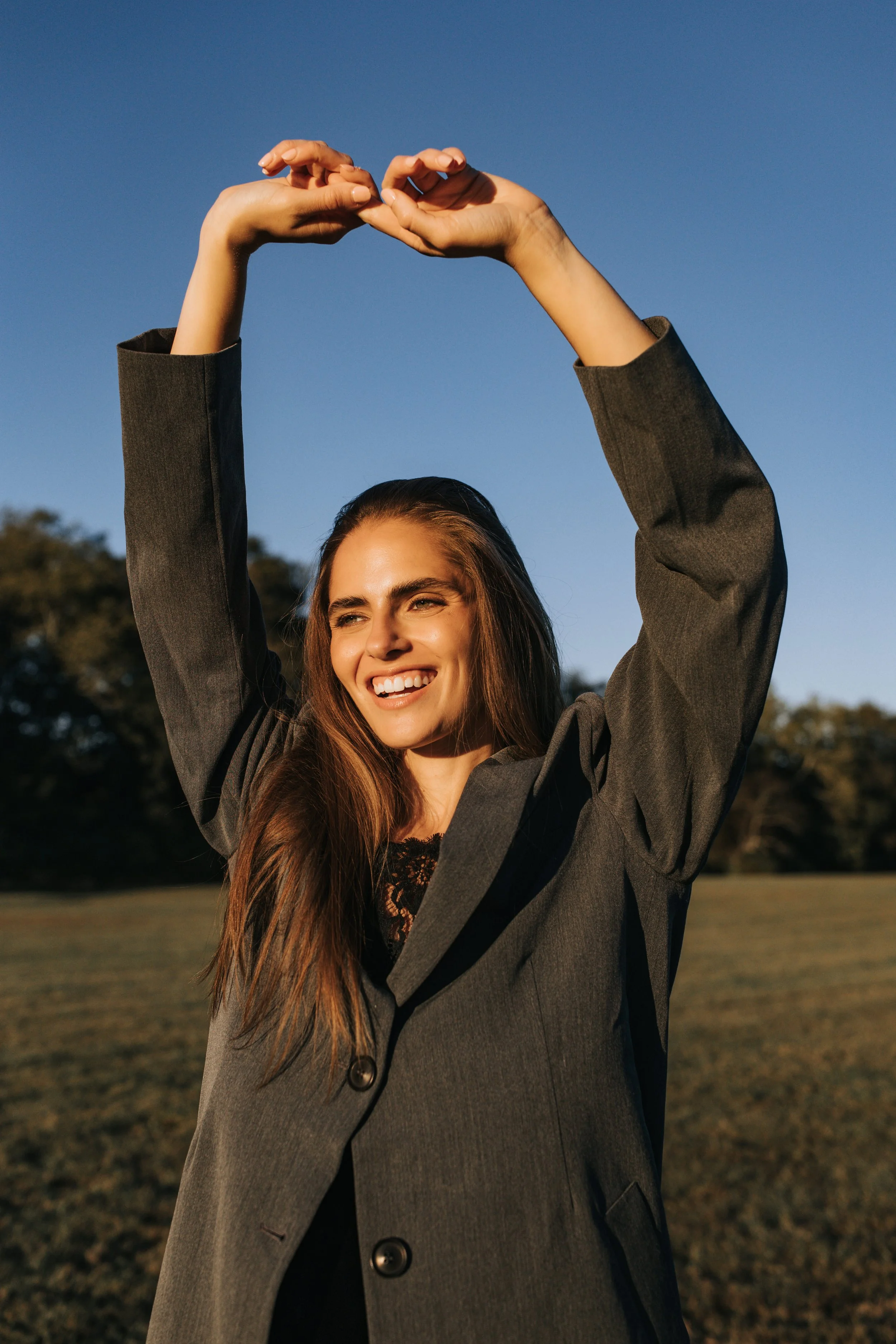  Model Skylar poses in a gray trench coat against a blue sky during her Nashville fashion photoshoot. 