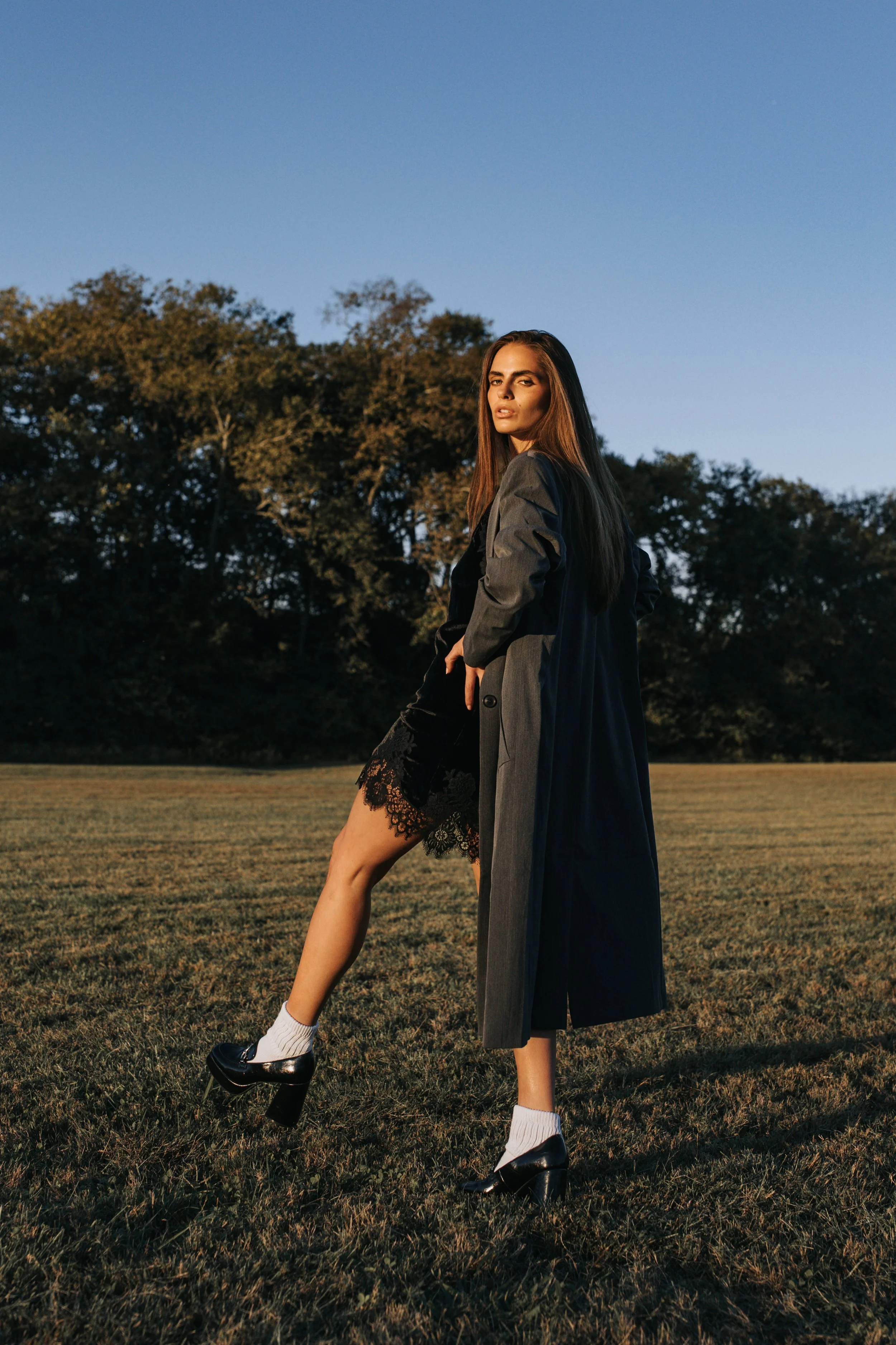 Model Skylar poses in a gray trench coat against a blue sky during her Nashville fashion photoshoot. 