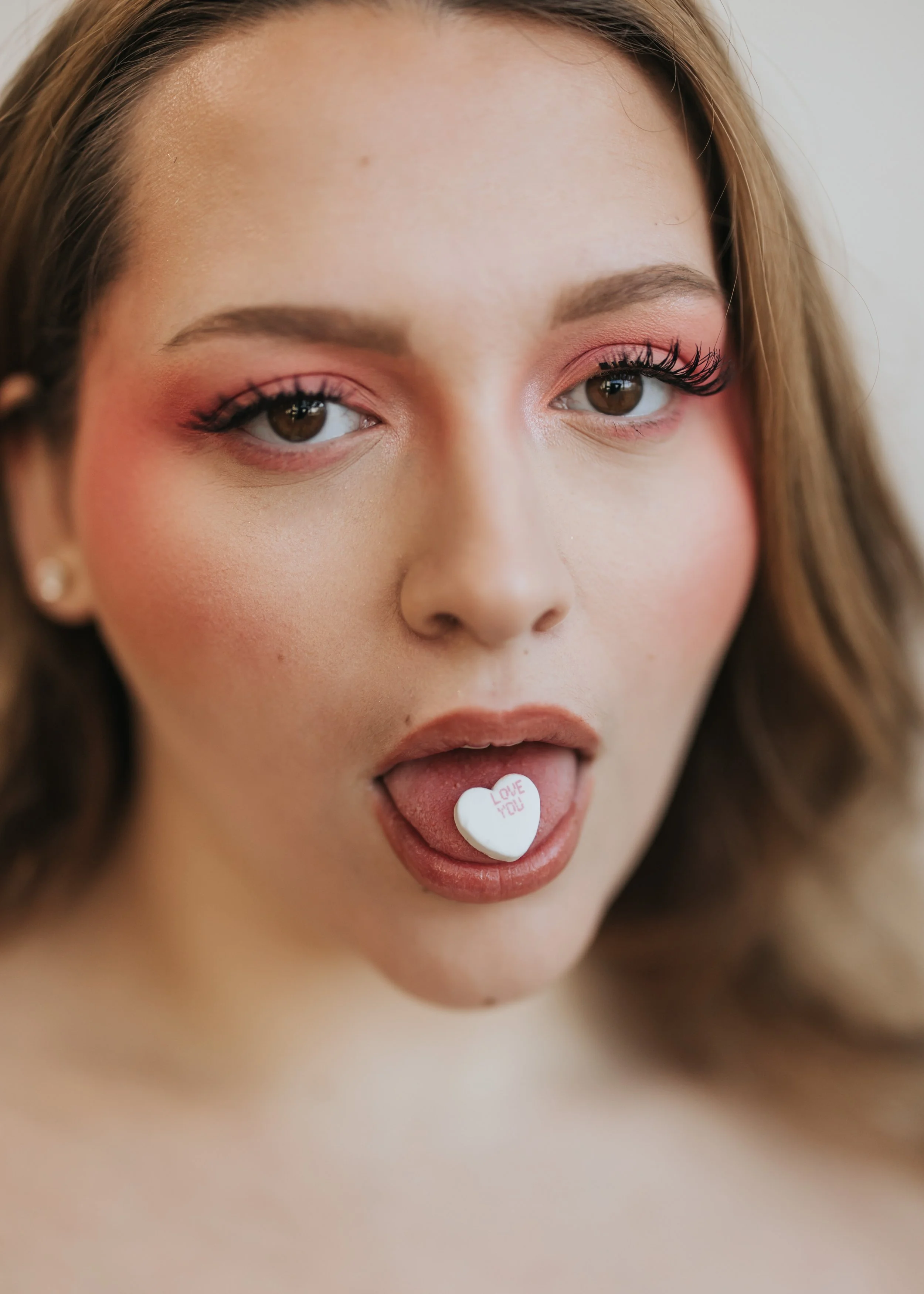 Fashion model poses with candy heart for a Valentine's Day photoshoot.