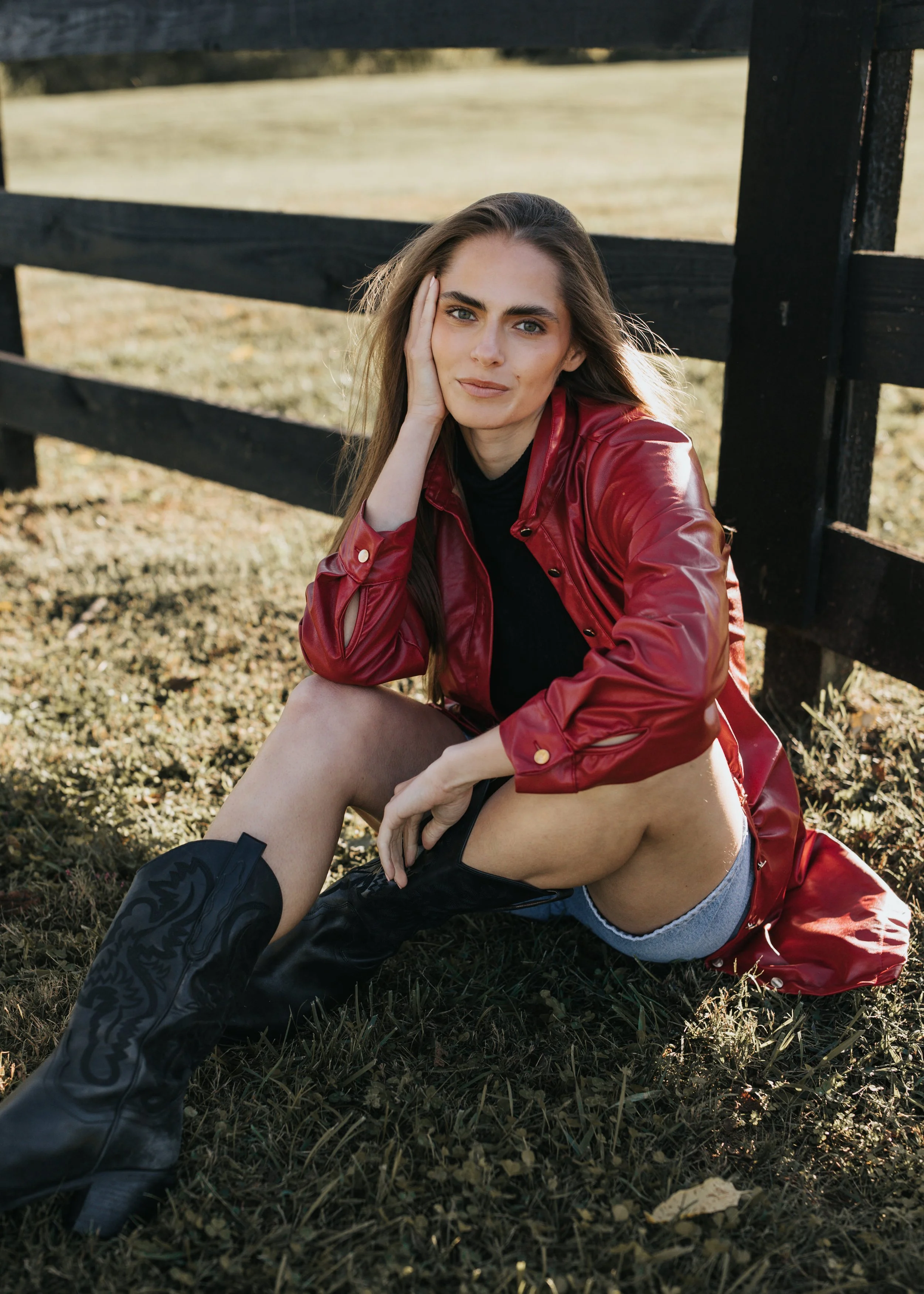  Model Skylar smiles while wearing a red jacket and sitting on the ground during her fashion photoshoot in Nashville. 