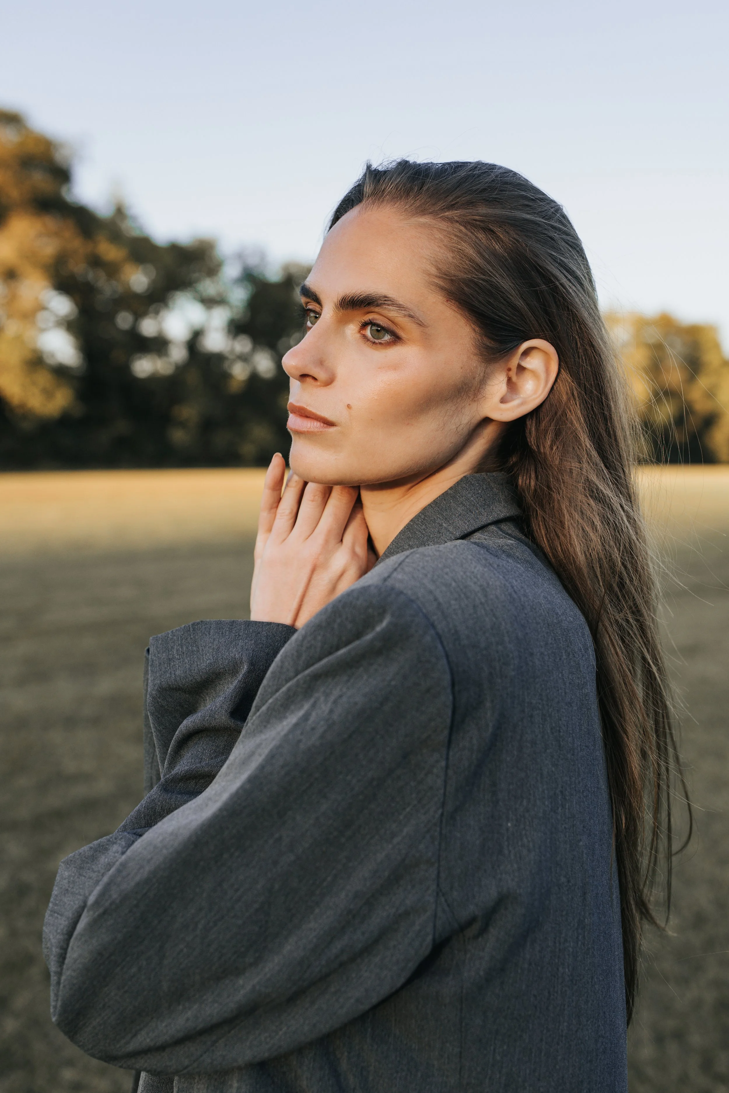  Model Skylar poses in a gray trench coat against a blue sky during her Nashville fashion photography test shoot. 
