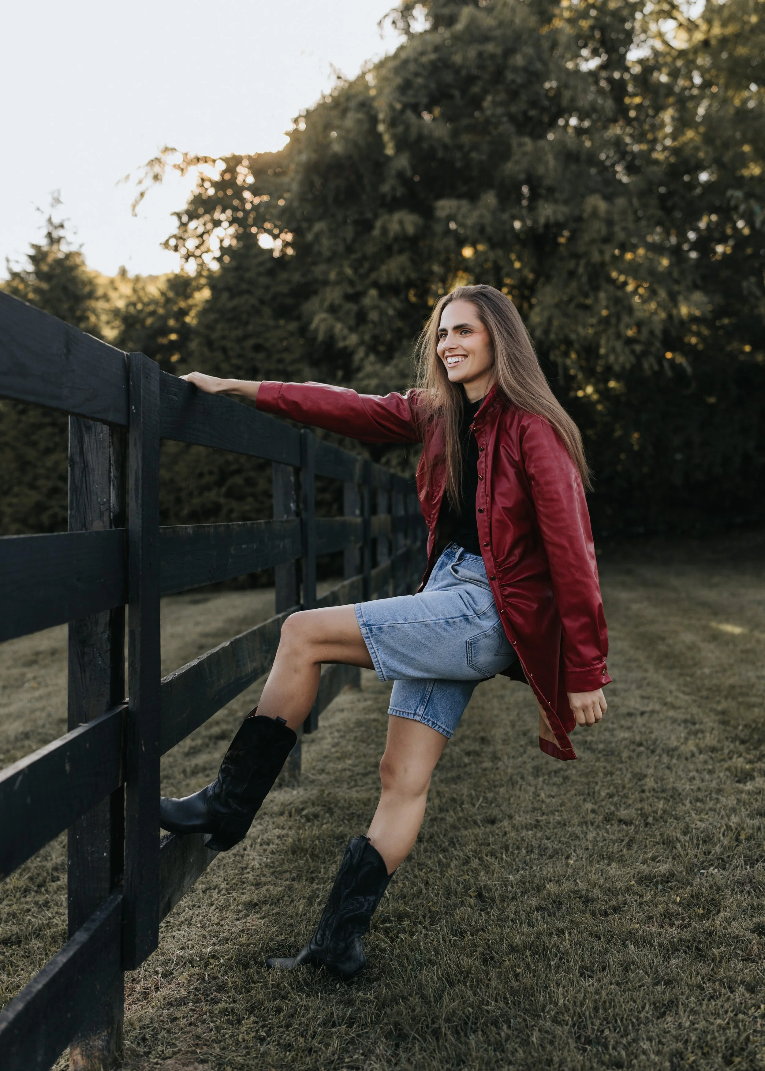  Model Skylar poses against a fence wearing a red jacket and denim shorts during her Nashville fashion photoshoot. 