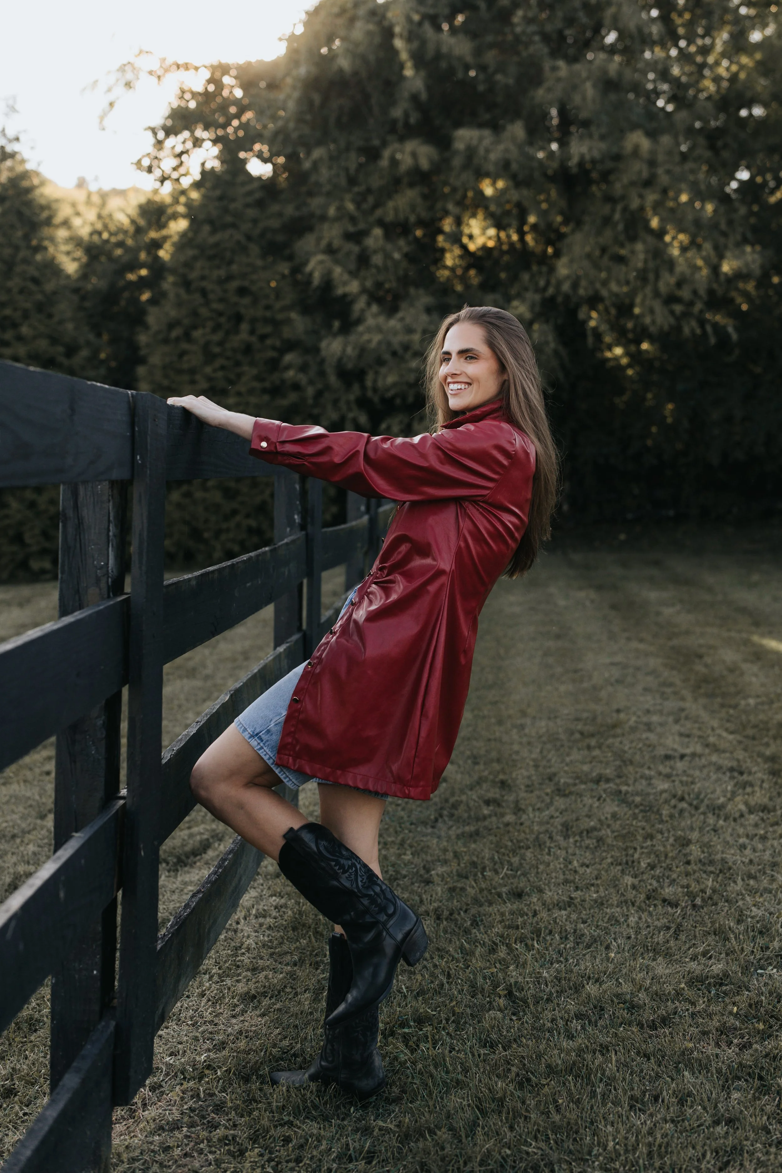  Model Skylar poses against a fence wearing a red jacket and denim shorts during her Nashville fashion photoshoot. 