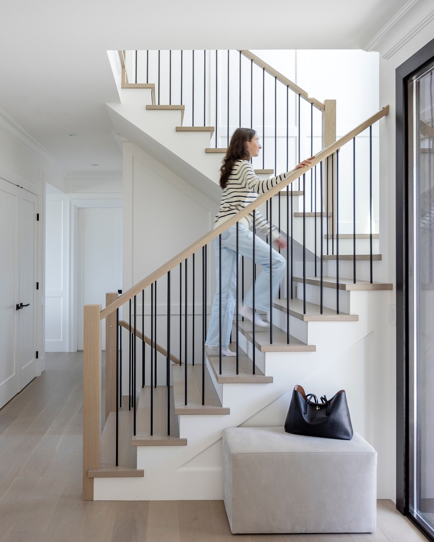 A staircase that makes an entrance.
White oak railings meet matte black spindles for a clean, contemporary look &mdash; softened by timeless wainscotting that adds just the right amount of character. Proof that contrast creates harmony. 

Interior De