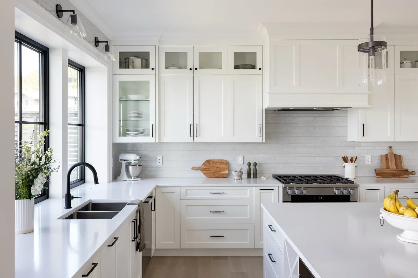 A custom kitchen that feels both timeless and refreshing. 🤍 Classic white shaker cabinets meet the subtle texture of offset Ann Sacks brick tile, while black hardware and mullioned windows ground the space with contrast and clarity. Simplicity, elev