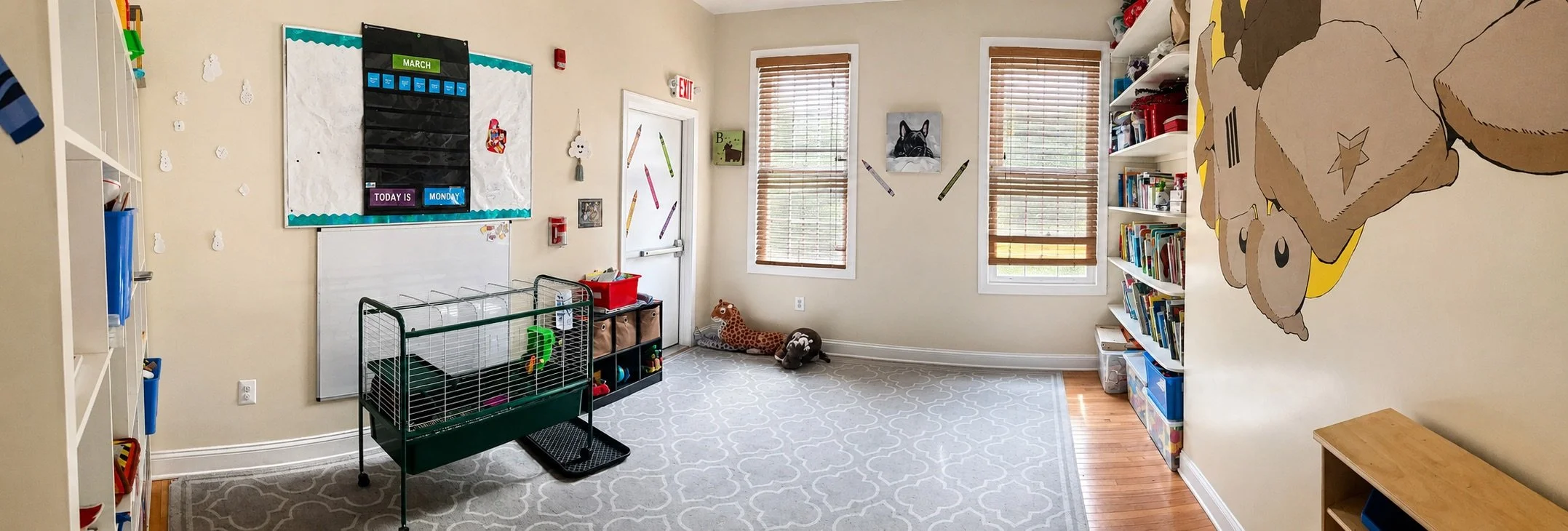 Bright classroom reading and activity area with books, educational materials, and open space for preschool children