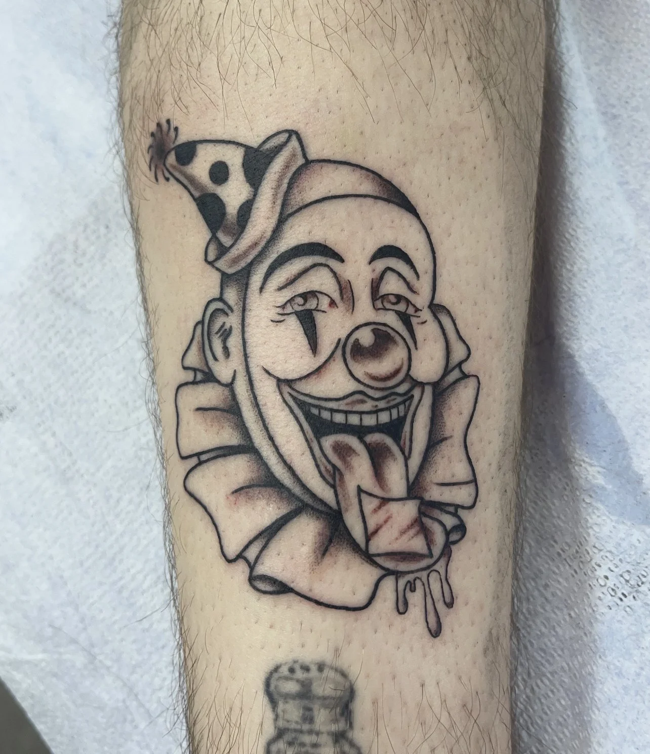 Clown head tattoo on the leg.