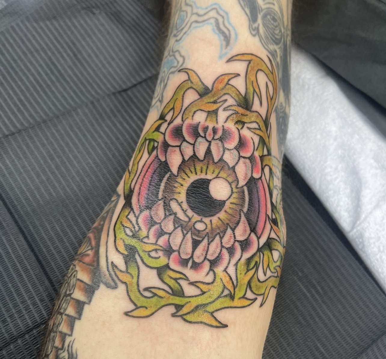 Eye in a mouth with vines in full color tattoo.