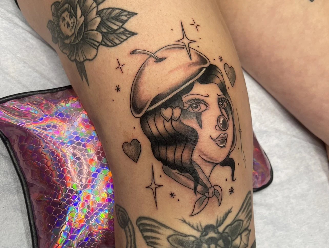Soft clown head tattoo with a beret hat.