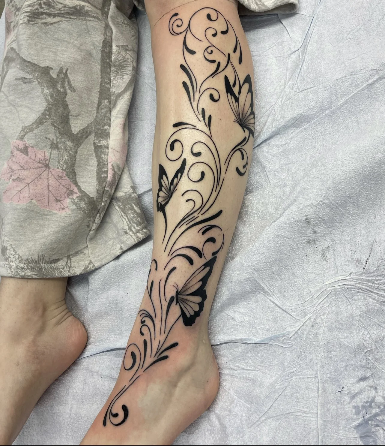 Art Nouveau vines and butterfly tattoo on the leg.