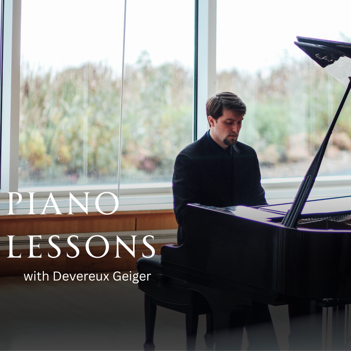A man playing a grand piano in a room with large windows and a view of trees outside.