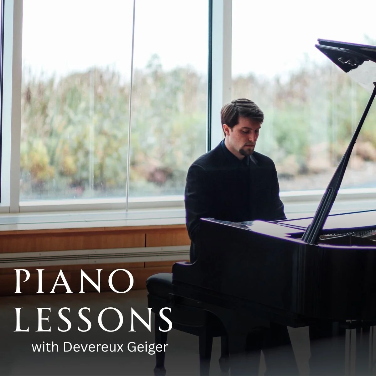 A man playing a grand piano in a room with large windows and a view of trees outside.