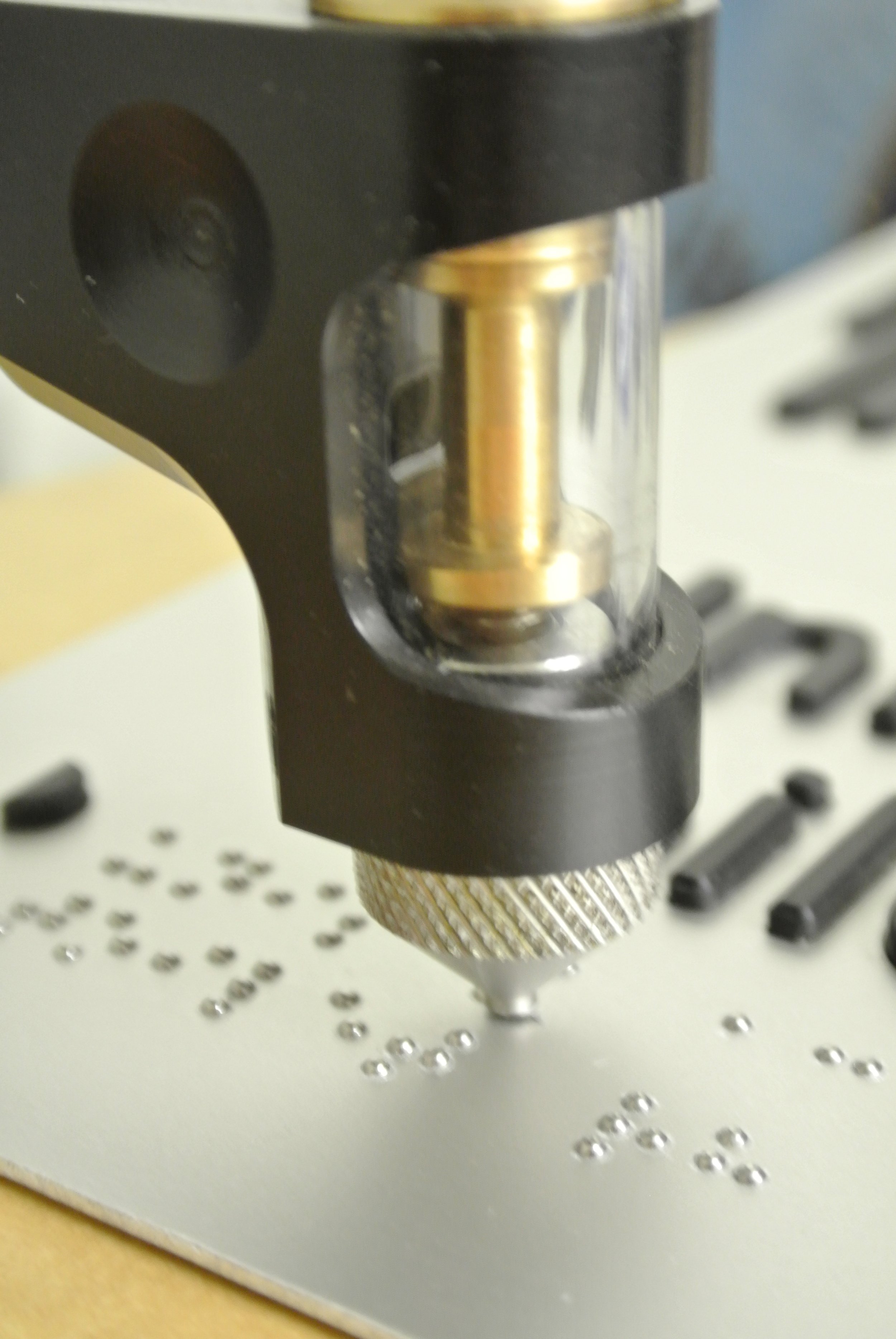 Close-up of a mechanical pinball machine part, showing a metallic component and a circuit board with small metallic dots.
