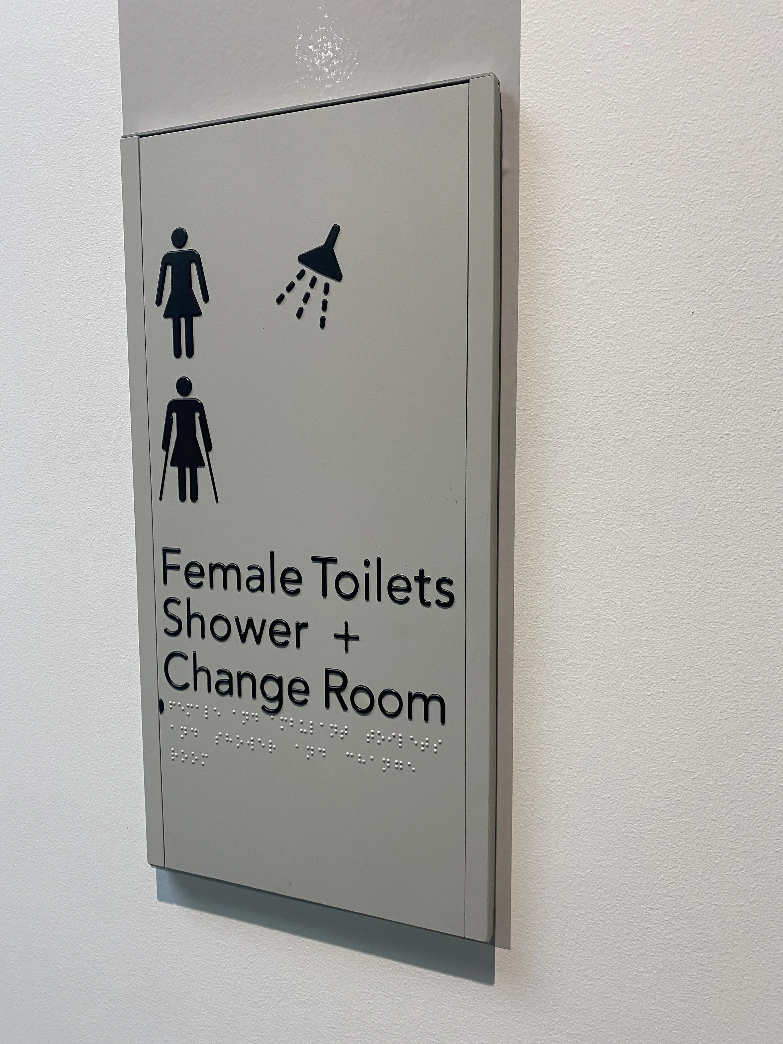 Sign indicating female toilets, shower, and changing room with braille beneath.