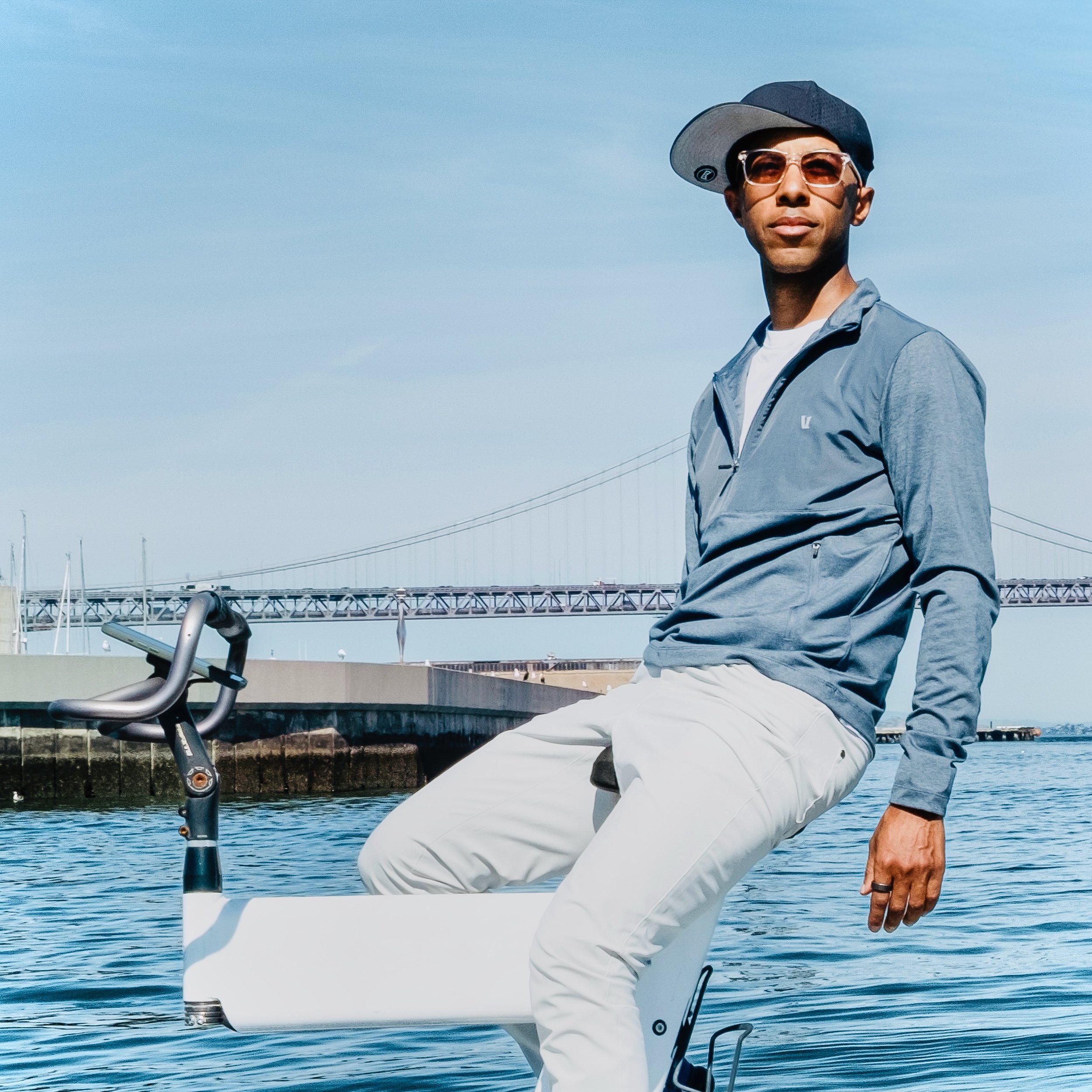 Damien sitting on a white Waterbike with water and the bay bridge in the background