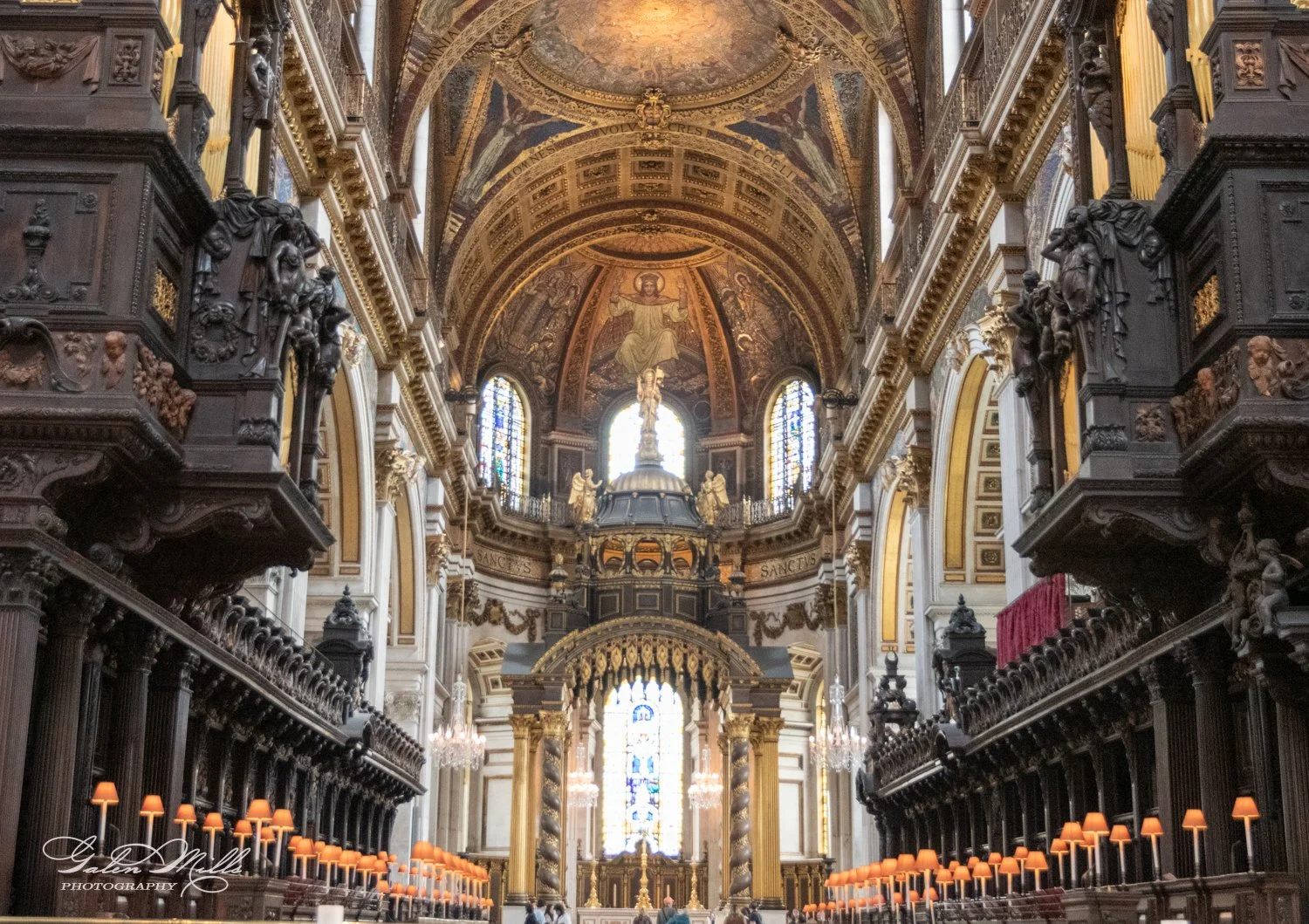 Interior view of a cathedral with an ornate altar, arched ceilings, and stained glass windows.