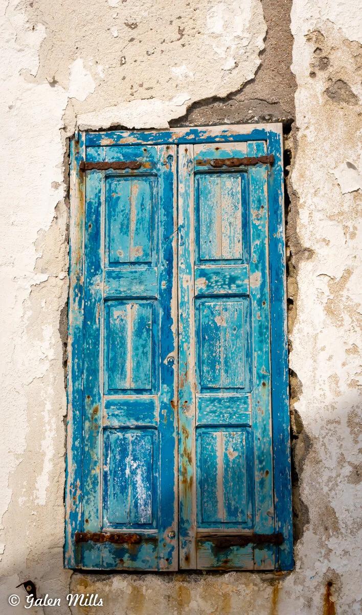 Old blue wooden shutters on a weathered wall.