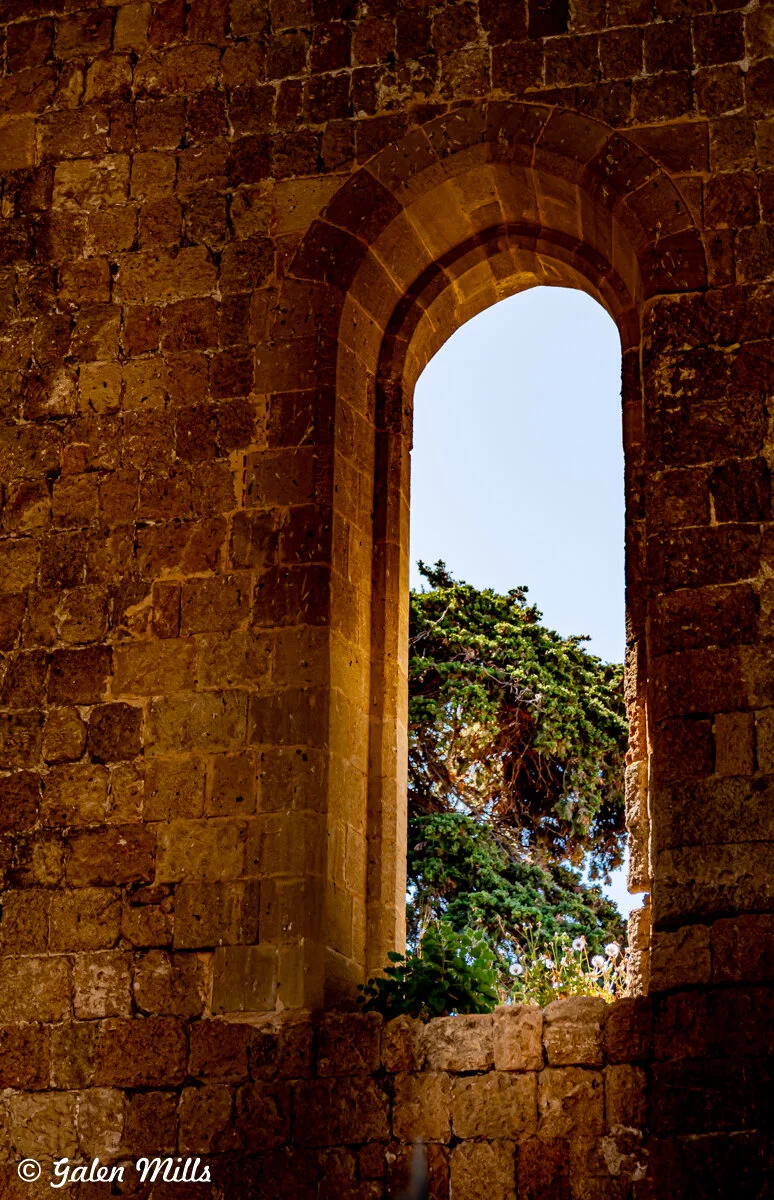Ancient stone archway with view of trees and sky