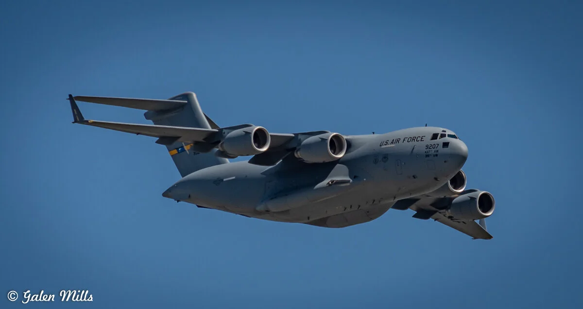 US Air Force C-17 Globemaster III in flight with clear blue sky background.