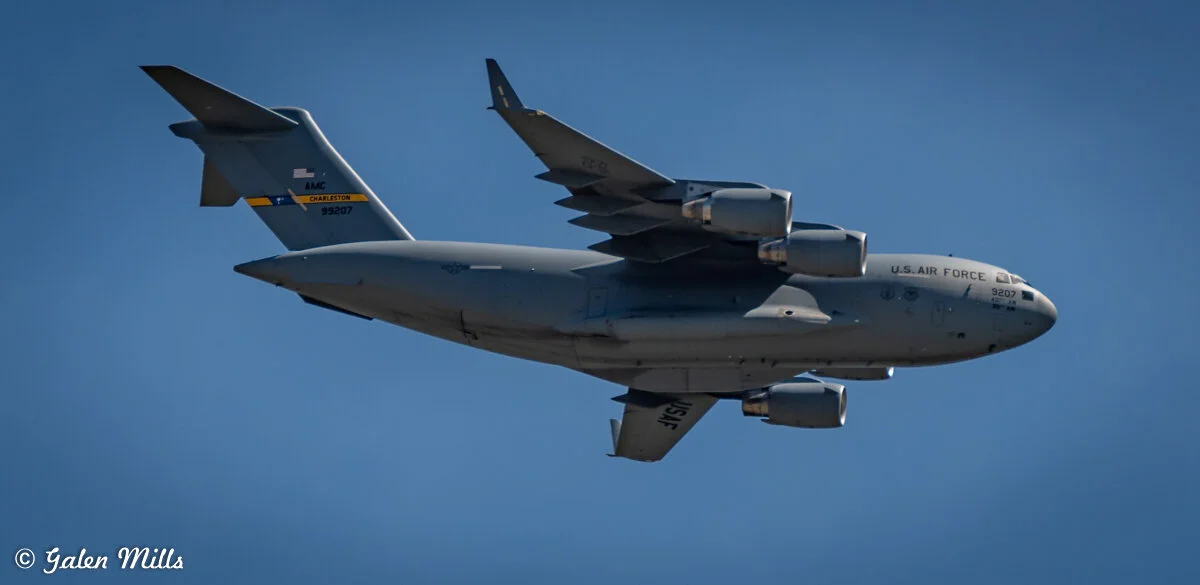 A U.S. Air Force C-17 Globemaster III aircraft in flight against a clear blue sky.