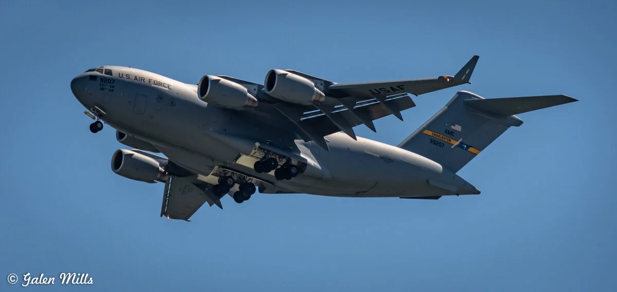 US Air Force C-17 Globemaster III airplane in flight against a clear blue sky.