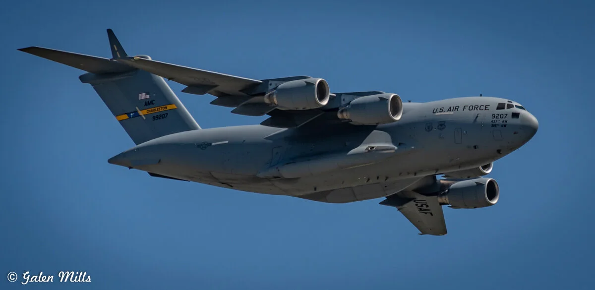 Close-up of a U.S. Air Force C-17 Globemaster III aircraft in flight against a clear blue sky.
