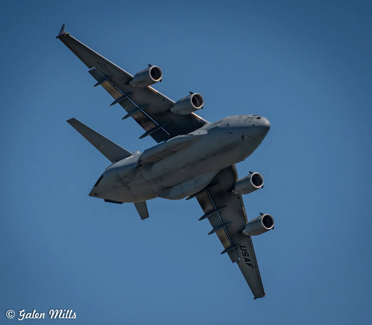 US Air Force military cargo plane flying overhead against clear sky
