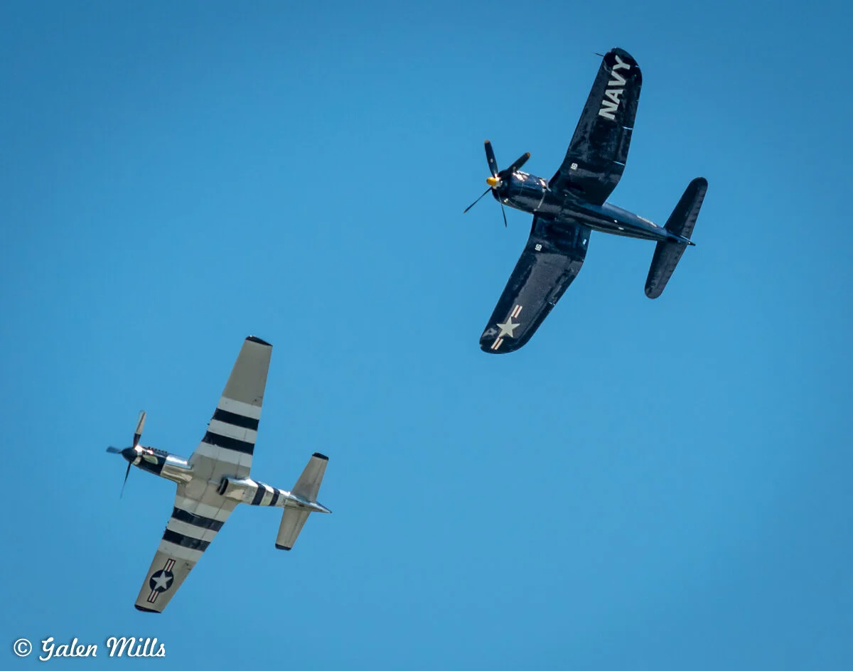 Two vintage military aircraft flying in formation against a clear blue sky.