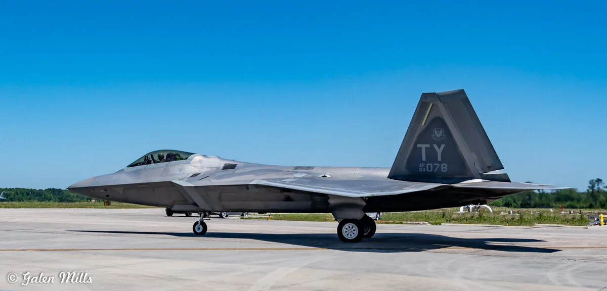 F-22 Raptor fighter jet on runway against clear blue sky