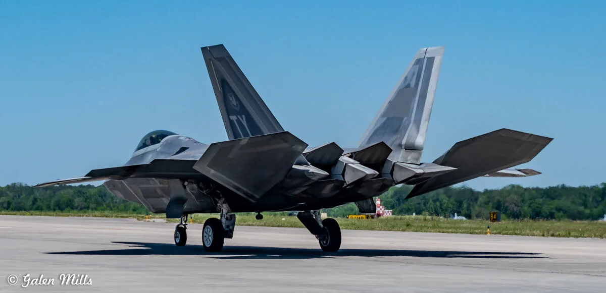 F-22 Raptor parked on airfield, tail view