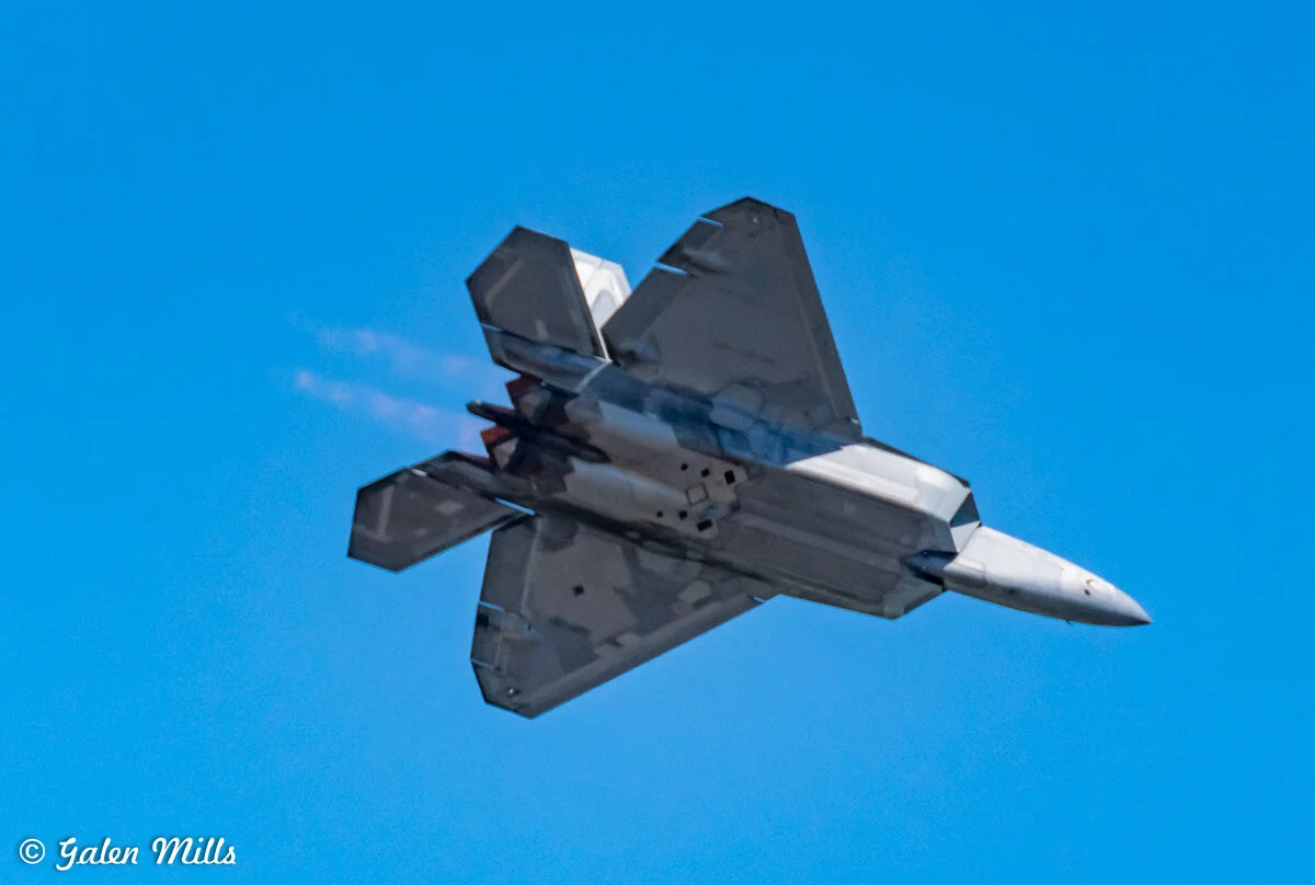F-22 Raptor stealth fighter jet flying in clear blue sky.