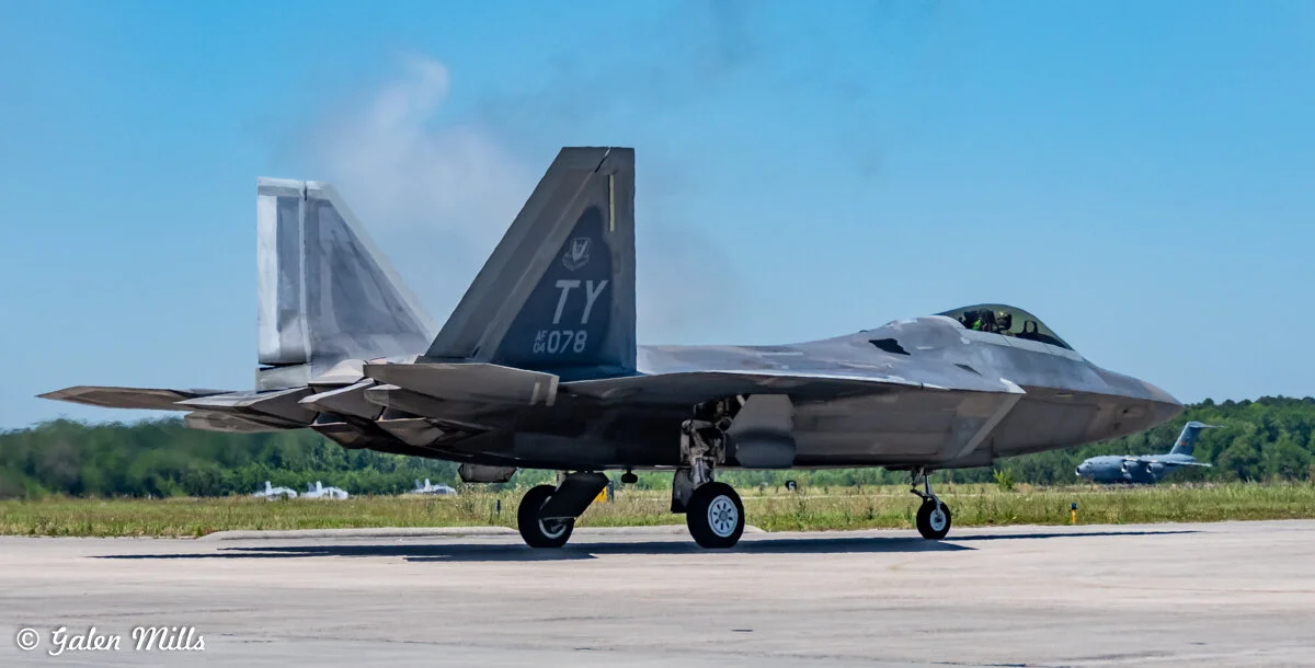F-22 Raptor jet on tarmac with C-17 Globemaster in background