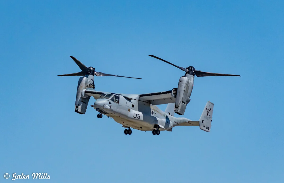V-22 Osprey aircraft in flight against a clear blue sky.