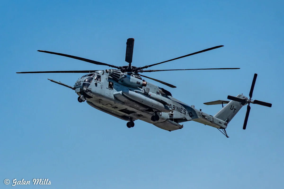 A military helicopter in flight against a clear blue sky.