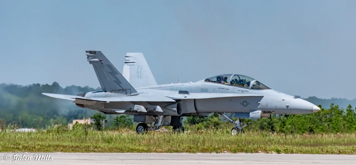 Military aircraft on runway with landing gear down.