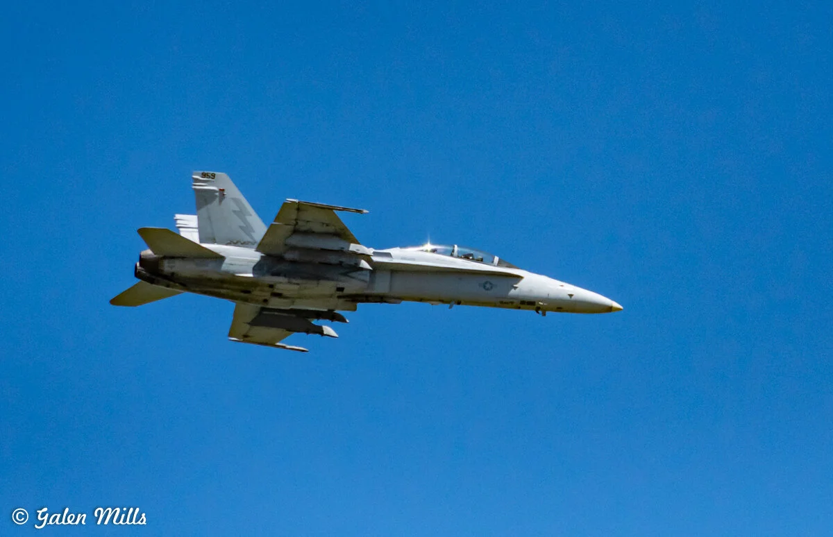 A military jet flying in a clear blue sky.