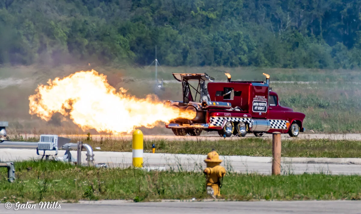 Custom red truck with jet engine shooting flames on an open road